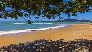 A beach with clear blue water, sandy shore, and distant mountains. - Pousada Penha (Penha)
