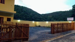 Una propiedad amurallada con un edificio amarillo, un cartel que dice "Pousada Alejandro" y montañas al fondo.