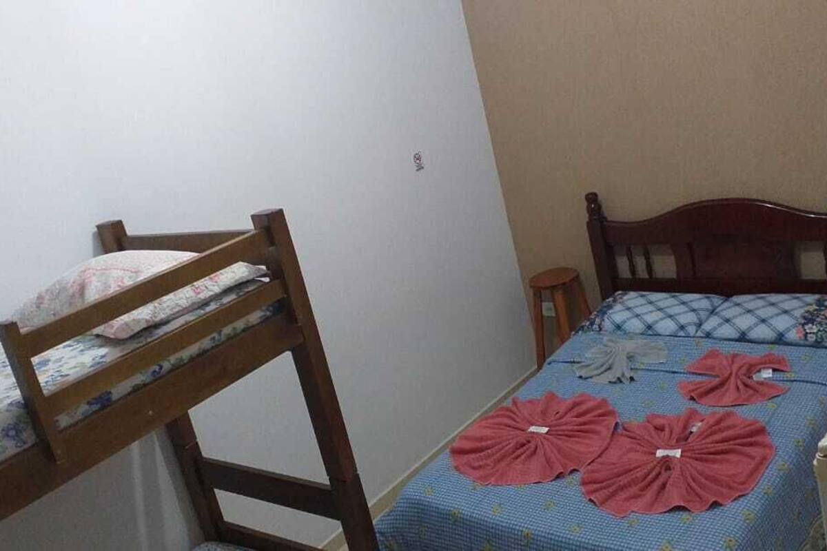 A small room with a bunk bed, a single bed, and a desk.