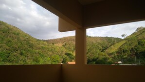 Vista desde un balcón sobre una ladera verde y exuberante bajo un cielo despejado.