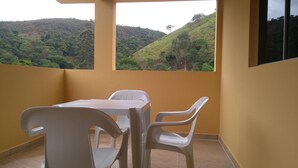 Un balcón con mesa y sillas, con vistas a un paisaje montañoso.
