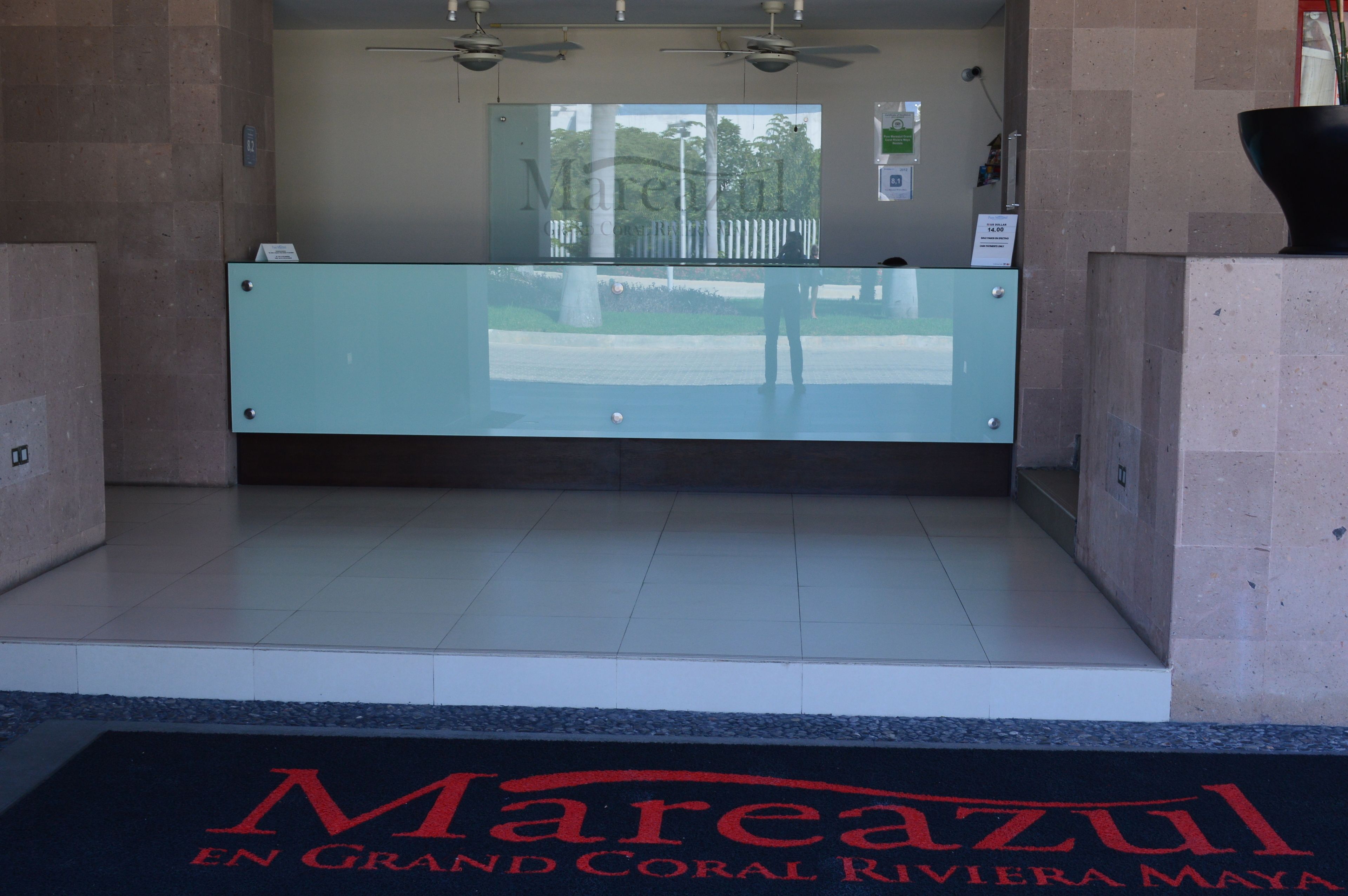 A reception area with a glass counter, a reception desk, and a sign indicating a price of $14.00.
