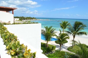 A resort with a white building, a beach, and palm trees.