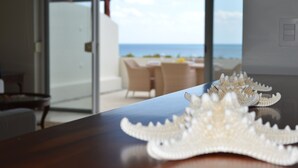 Een eettafel met een decoratief middelpunt en uitzicht op een strand door een glazen deur.