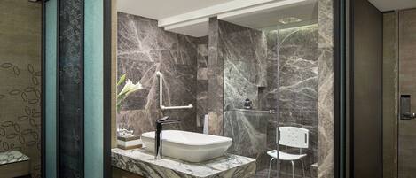 A modern bathroom with a marble sink, glass shower enclosure, and a wooden vanity.