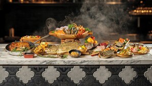 Une variété de plats sont disposés sur une table en marbre, notamment un poisson entier rôti, des fruits de mer et différentes salades.