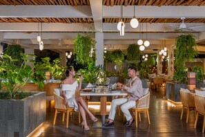 Un restaurant doté d’un plafond en bois, de plantes suspendues et d’un éclairage moderne.