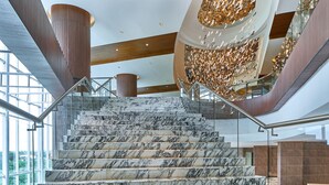 Un magnifique escalier en marbre mène à un intérieur moderne agrémenté de touches de bois et doté d’un plafond au design unique.