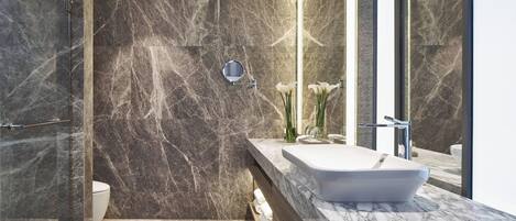 Un baño moderno con tocador de mármol, un espejo grande y un inodoro.