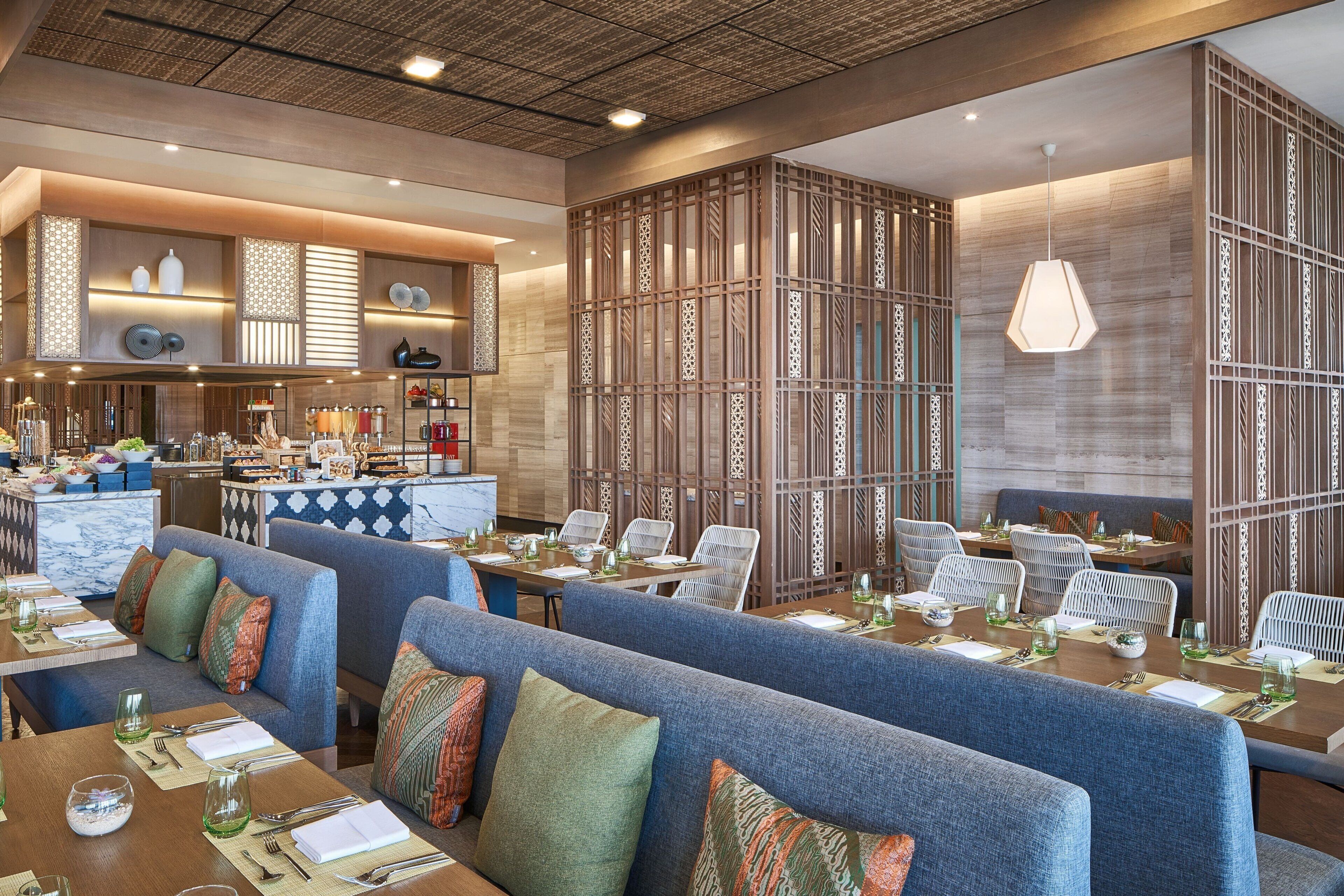 A modern restaurant with blue upholstered seating, wooden partitions, and a variety of table settings.