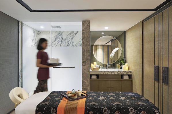 Una habitación de hotel moderna con cama, baño con tocador de mármol y un espejo grande.