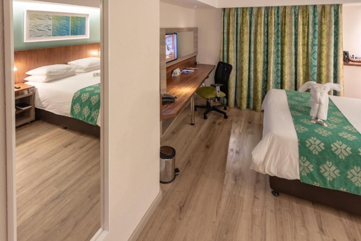 A hotel room with a bed, a desk, a chair, and a window with curtains.