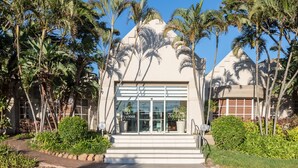 A hotel entrance with a modern design, featuring a glass facade and palm trees. - City Lodge Hotel Durban (Durban)