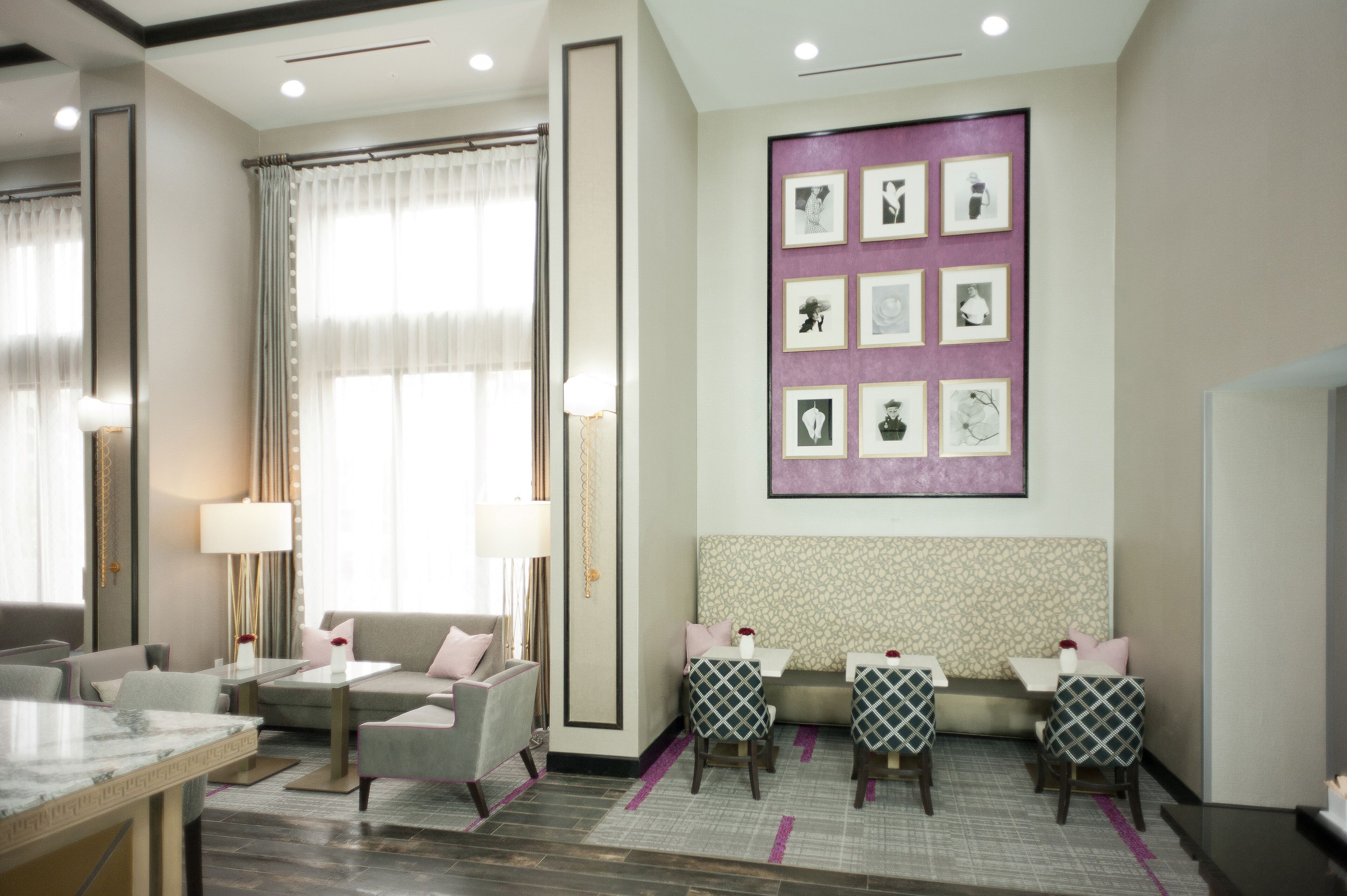 A hotel lobby with a seating area, a reception desk, and a wall with framed pictures.