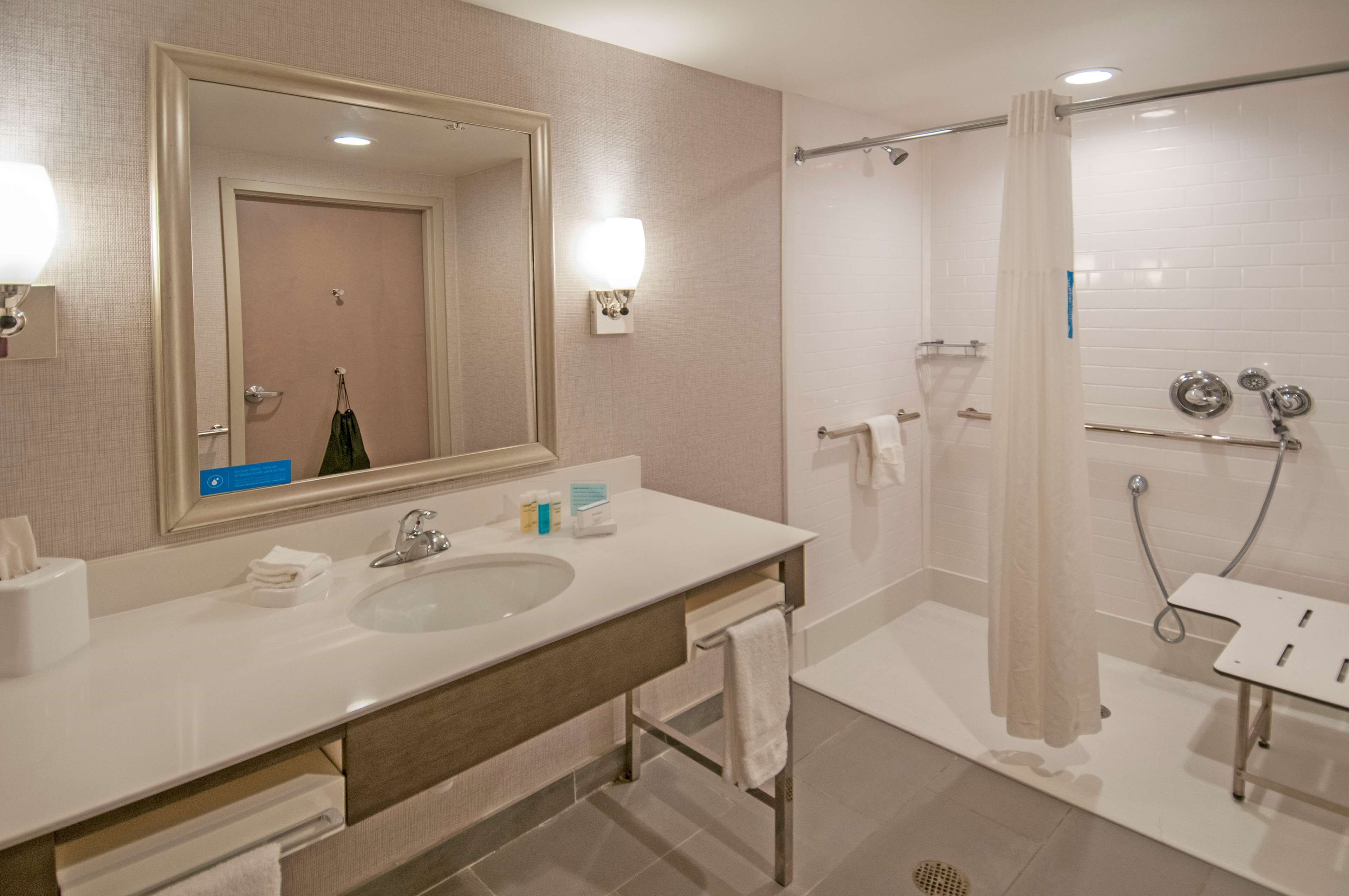 Un baño moderno con lavamanos doble, un espejo grande, ducha con puerta de cristal y toallero.