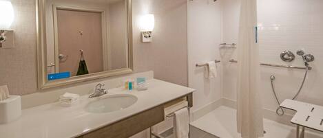 Un baño moderno con lavamanos doble, un espejo grande, ducha con puerta de cristal y toallero.