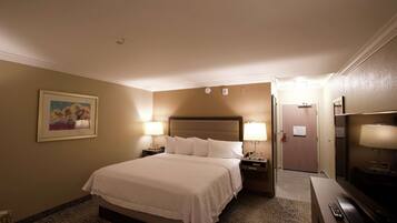 A hotel room with a large bed, two bedside lamps, a television, and a framed picture on the wall.