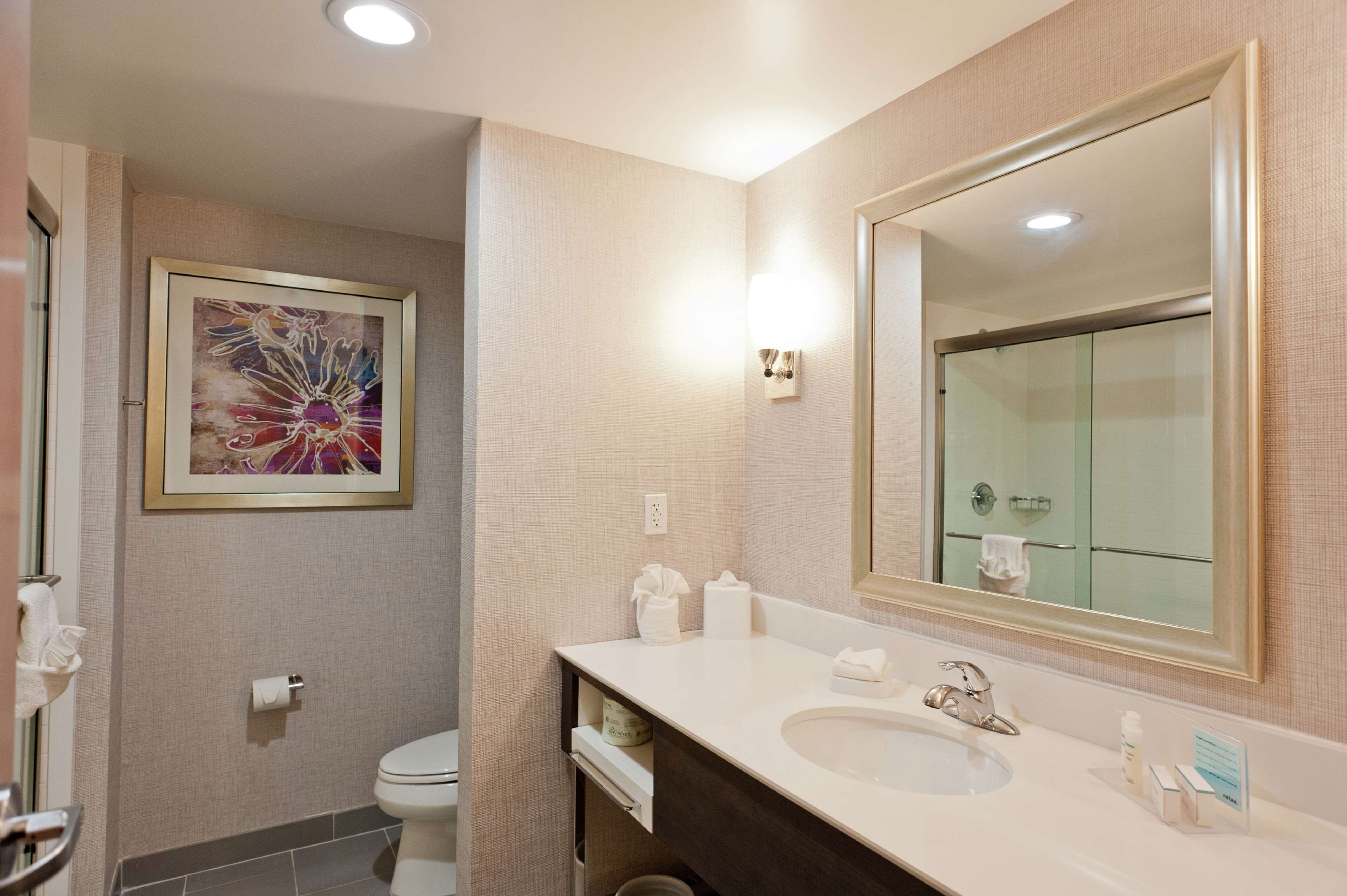 A modern bathroom with a large mirror, a sink, and a toilet.