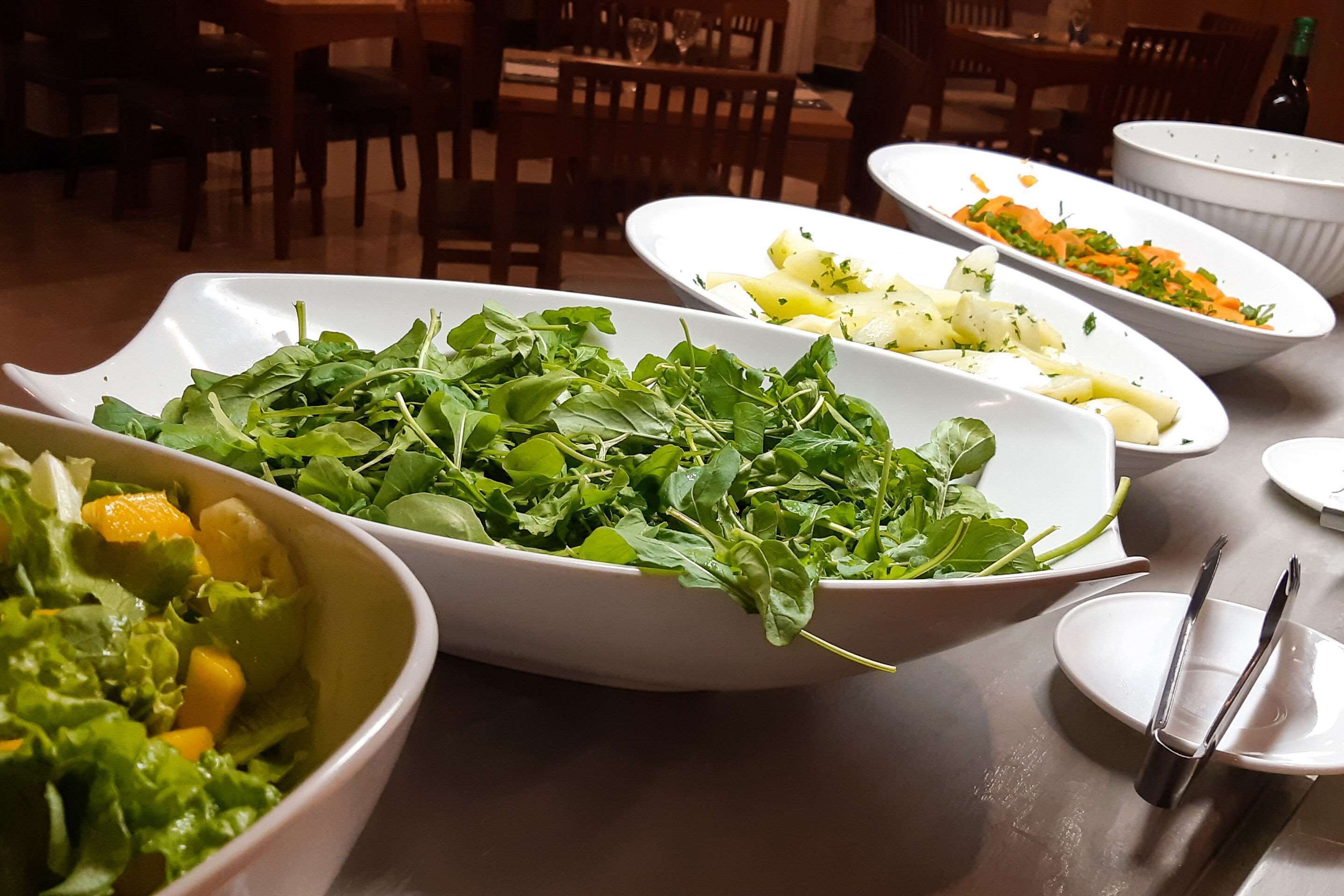 A dining table with various dishes including salads and vegetables.