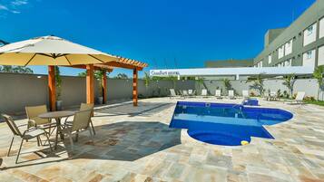 Relax by the clear pool surrounded by a patio and pergola with a canopy.