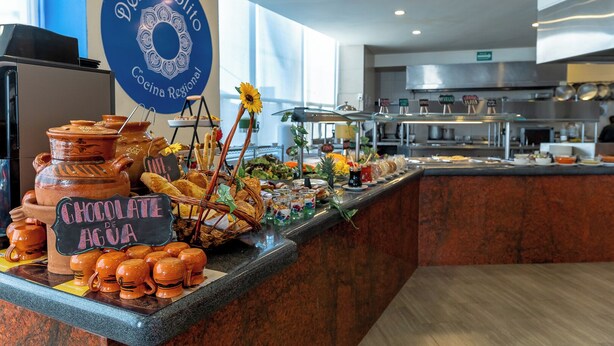 A buffet area with a sign reading "Del Pueblo Cocina Regional" and a variety of food items including chocolate de agua. - Hotel Misión Puebla Angelopolis (Puebla)