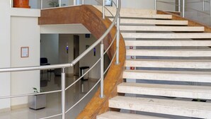 A modern interior with a curved wooden staircase and metal railings. - Hotel Misión Puebla Angelopolis (Puebla)