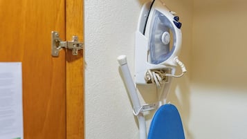 Una habitació amb una porta de fusta, una paret blanca i una taula de planxar blava amb un ferro.
