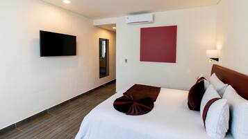 Een hotelkamer met een bed, een flatscreen televisie aan de muur, een rode accentmuur en een houten vloer.
