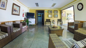 A spacious lobby with wicker furniture, a ceiling fan, and framed artwork on the walls. - Hotel Graúnas (São Carlos)