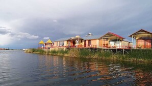 A waterfront property with multiple buildings, some with red roofs and others with yellow roofs, connected by a wooden walkway over water.