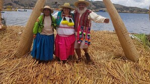 A group of people standing in a straw arch formation.