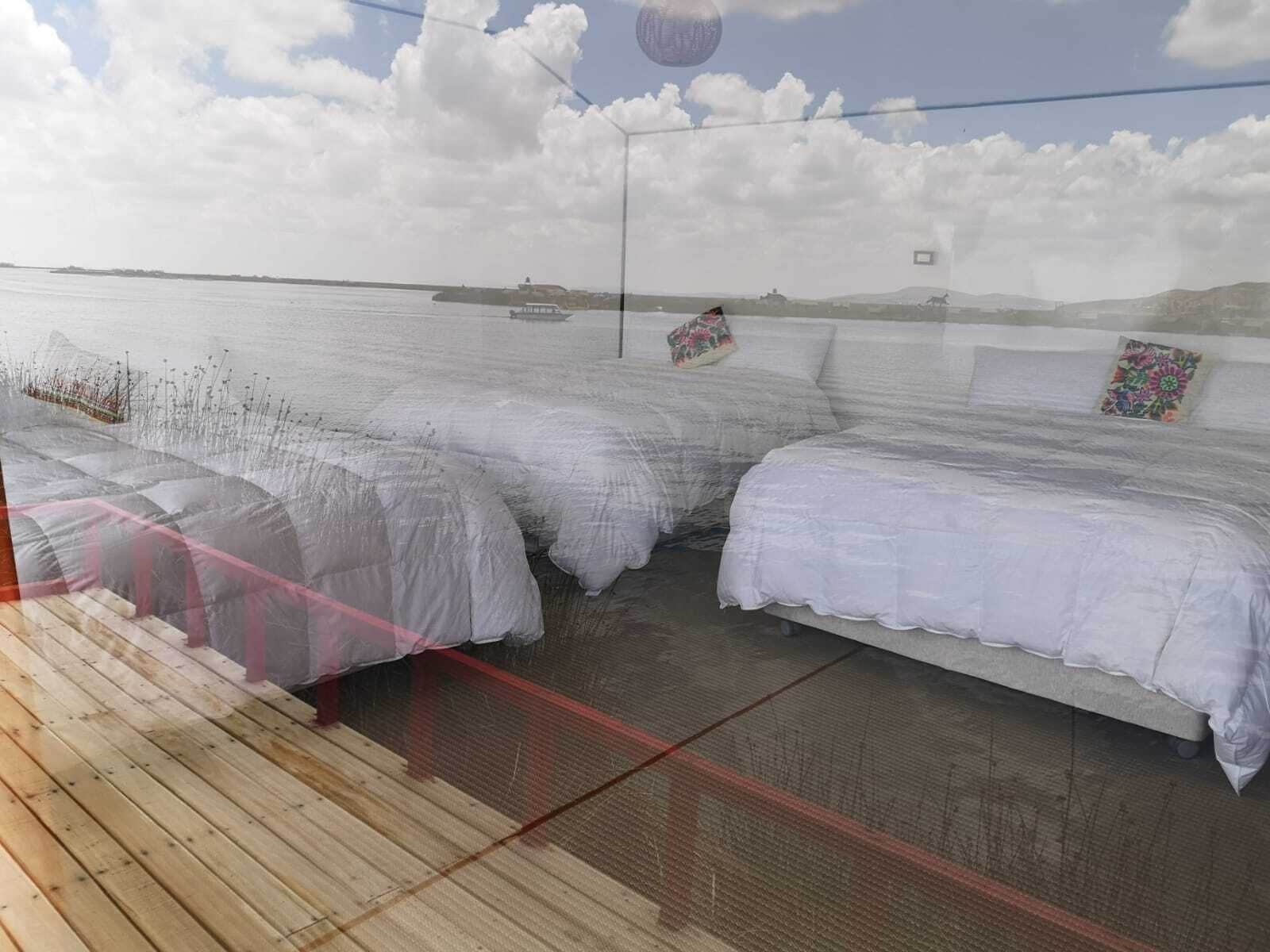 Una habitación con dos camas, vista al mar y una terraza de madera.