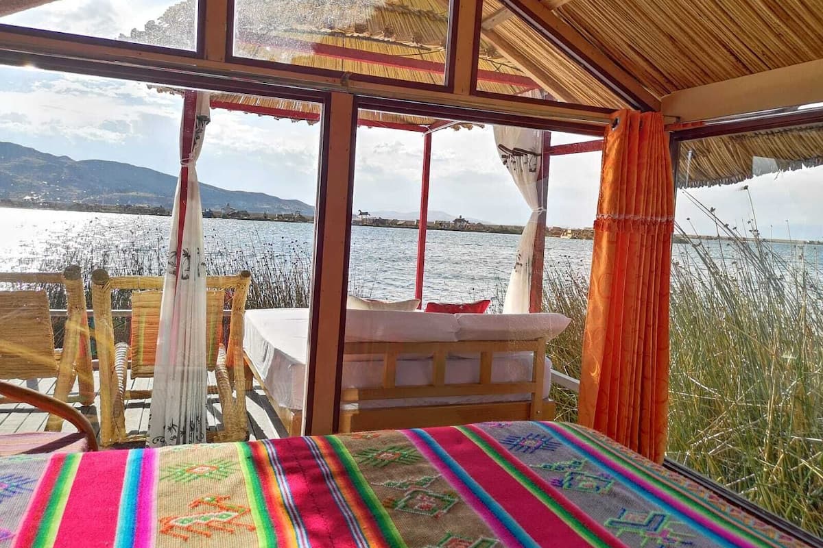 Una habitación con cama, una mesa y vistas a un lago y montañas.