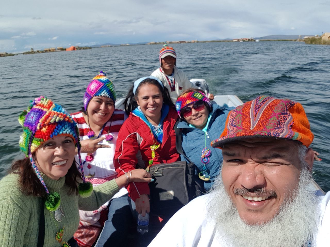 A group of people on a boat with a body of water and distant land in the background.