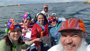 A group of people on a boat with a body of water and distant land in the background.