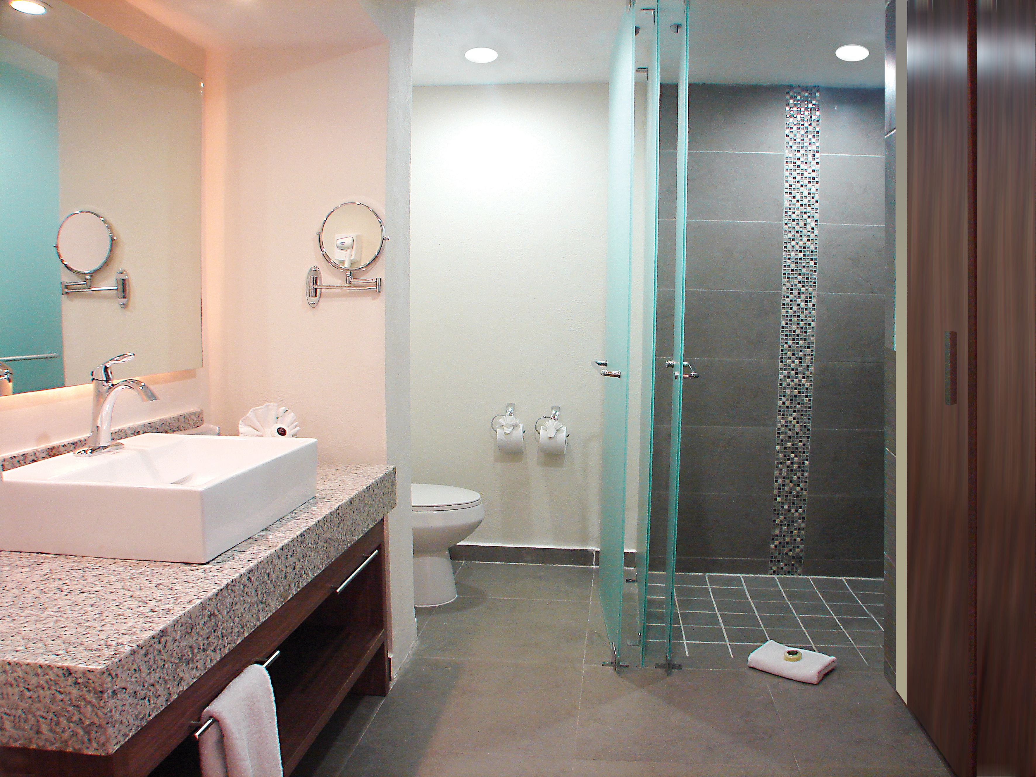 A bathroom with a large sink, toilet, and a glass-enclosed shower.