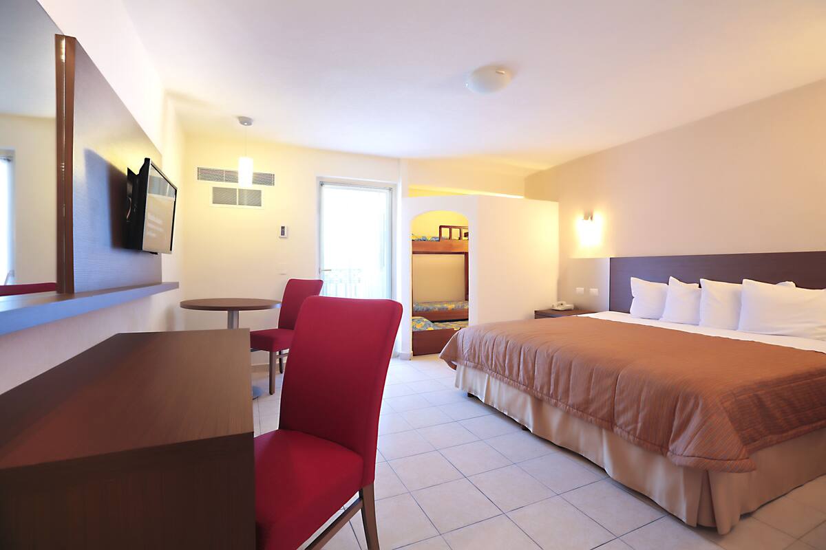 Una habitación de hotel con cama, escritorio, silla y televisor.