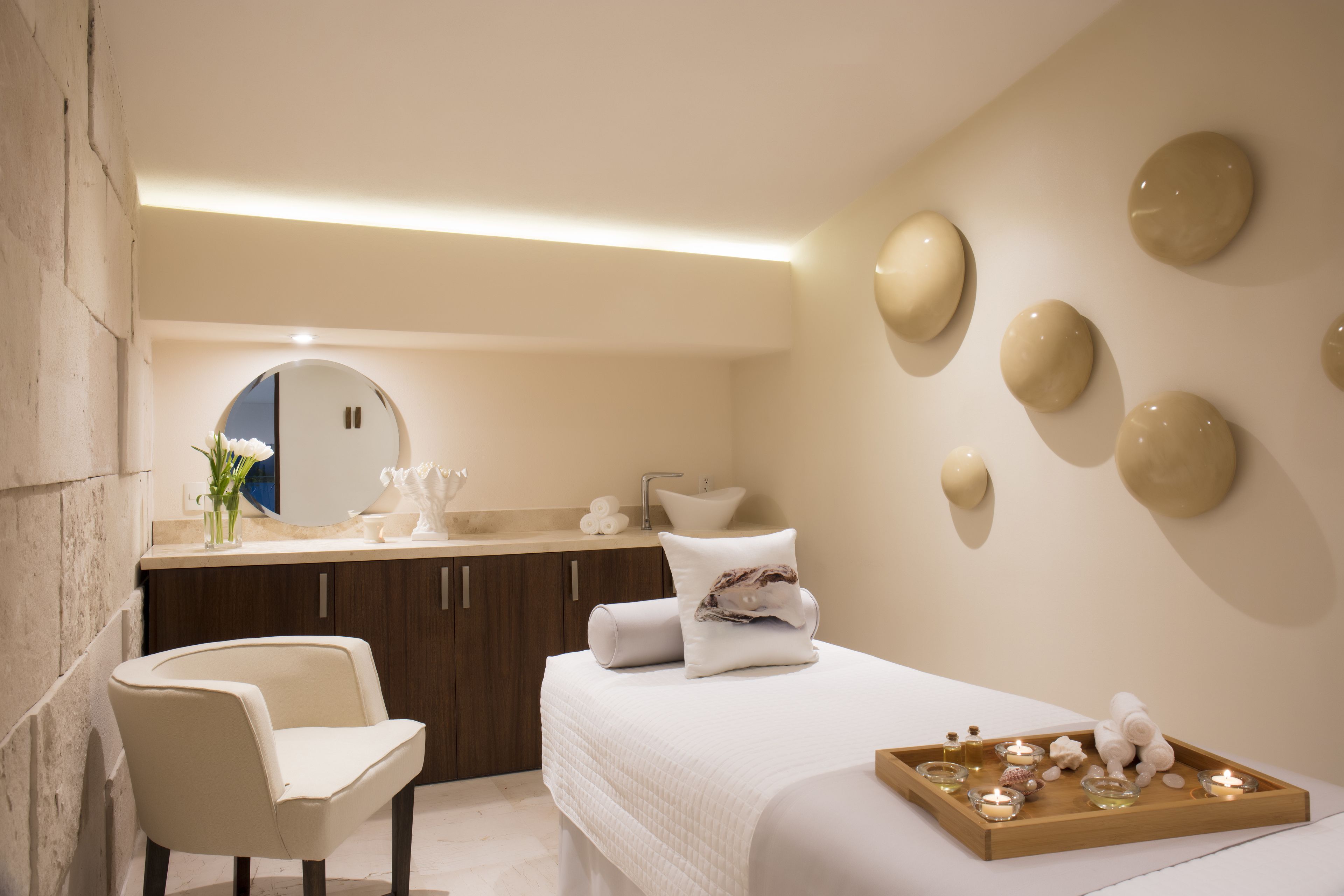 Un baño moderno con un espejo grande, un lavabo redondo y una cama con toallas.