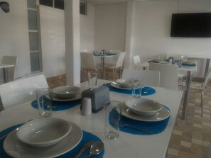 A dining area with tables set for four, each with white plates, clear glasses, and blue placemats. - Hotel CSI Medellín (Medellín)