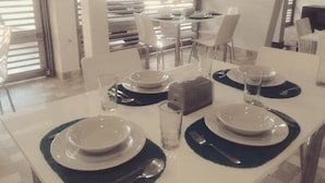A dining table set with plates, glasses, and cutlery, with a view of the outdoor area through large windows. - Hotel CSI Medellín (Medellín)