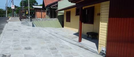 Uma rua com calçamento de pedra, edifícios com fachadas verdes e amarelas, e um portão vermelho.