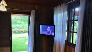 A room with a television mounted on the wall, a door leading to an outdoor area, and a patterned rug on the floor. - Residencial Serra Grande Gramado (Gramado)