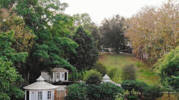 A garden with a gazebo, a small white building, and a fenced area.
