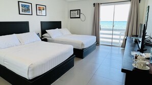 A hotel room with two beds, a desk with a TV, and a view of the sea. - Playa Azul Baler (Baler)