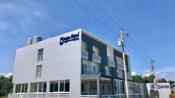 A two-story building with a flat roof and a sign reading "Playa Agust Hotel".