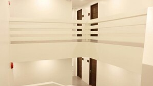 A multi-level interior with white walls and doors, featuring a central staircase and multiple doorways. - Playa Azul Baler (Baler)