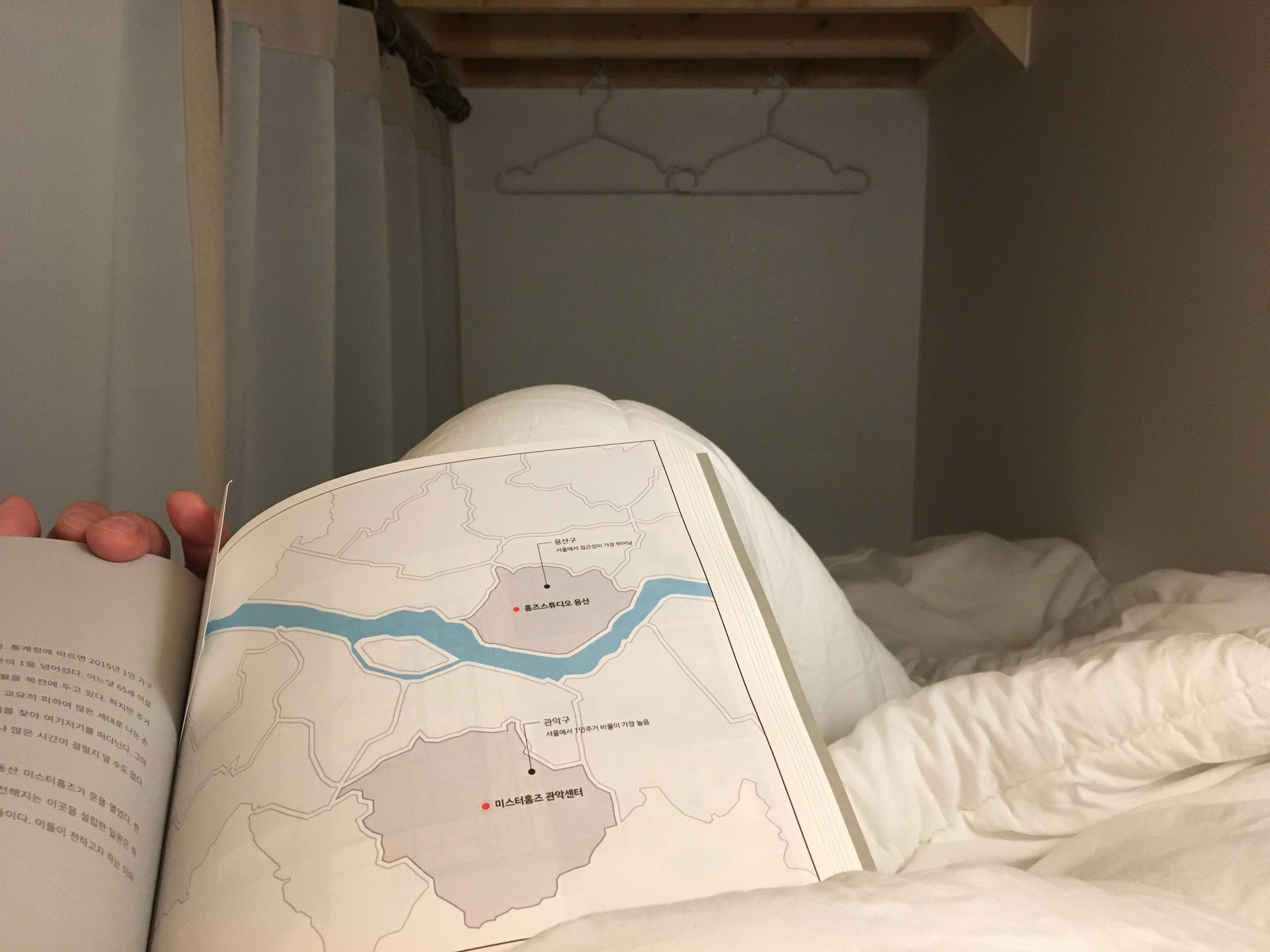 A book with a map, a bed, and a wooden shelf.