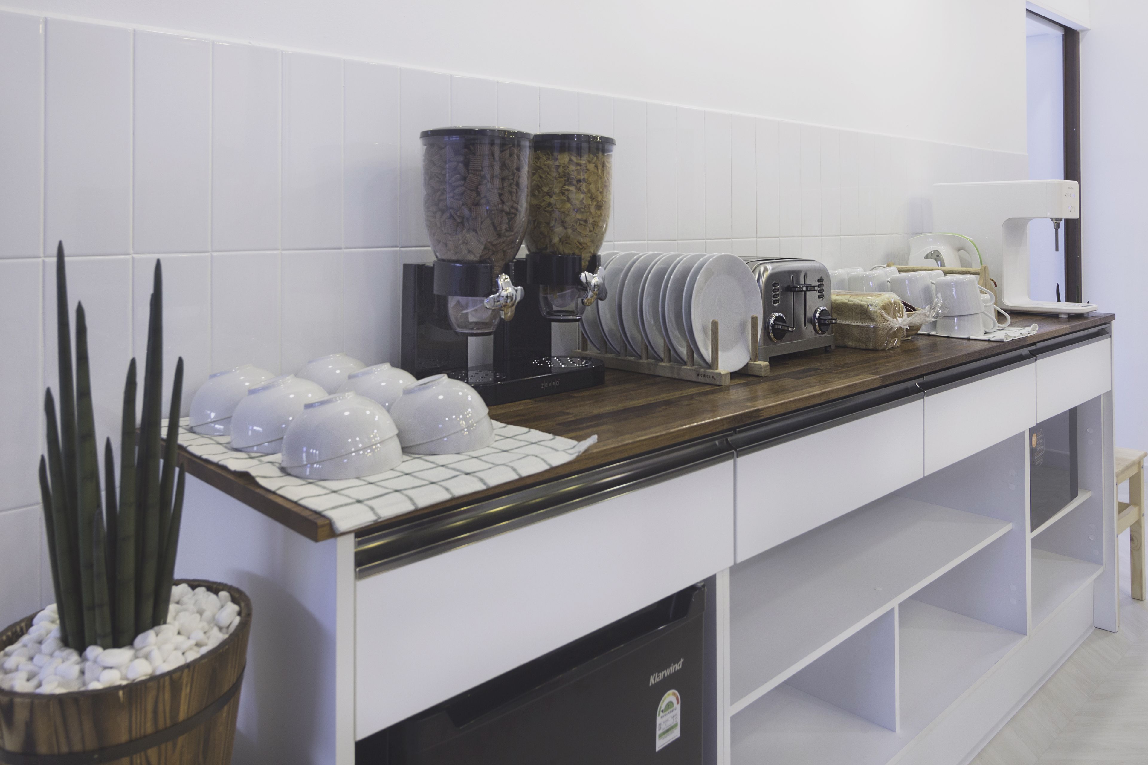 A kitchen with white cabinets, a wooden countertop, a coffee machine, a toaster, and a potted plant.