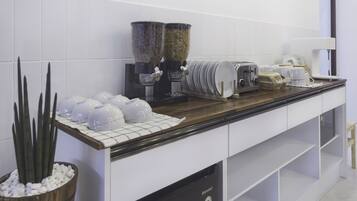 A kitchen with white cabinets, a wooden countertop, a coffee machine, a toaster, and a potted plant.