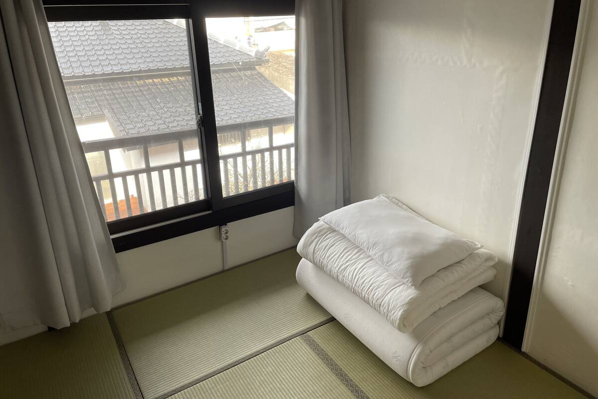 A room with a bed, a window, and a tatami mat floor.